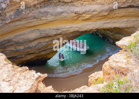 Tourists visiting inside of Benagil Caves on the tour boats viewed through the hole from above. Stock Photo