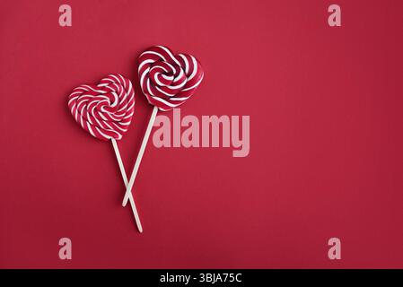 Heart lollipops candy on a stick on red background with copy space, top view, Valentine's day concept. Stock Photo
