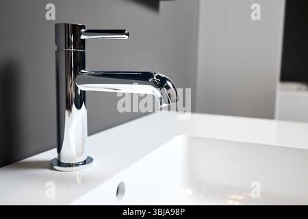 Interior detail of bathroom with washbasin sink with square drain and faucet. Bathroom interior sink with gray tiled wall and mirror modern flat minim Stock Photo