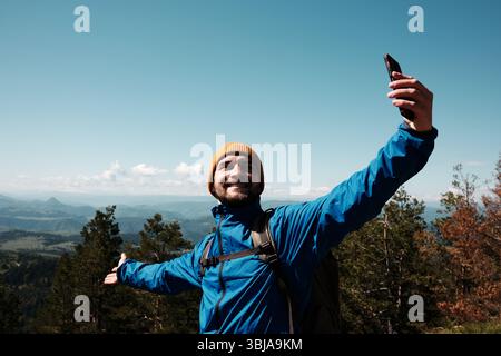 Happy tourist stretching arms wide for a selfie, enjoying the scenic view from Tornik peak. Serbia country during spring. Travel blogger making video Stock Photo