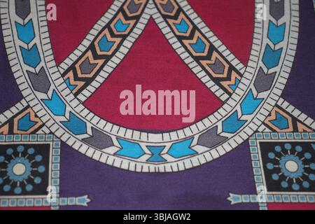 A vivid textile design featuring interwoven geometric patterns in rich shades of red, blue, purple, peach, black, and white. Stock Photo