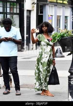 Woman using a smart phone to record a video of street entertainment in Wellington Stock Photo