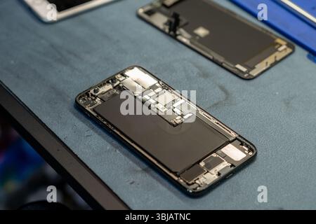 Expert Phone Repair Under Way on a Workbench With Disassembled Smartphone Components and Tools Present Stock Photo