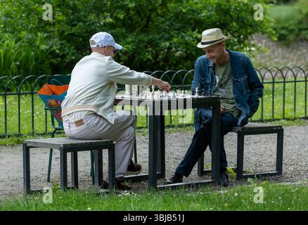 Two elderly men playing chess in a public park in summer Stock Photo
