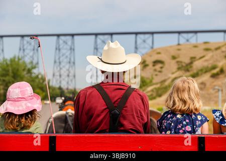 Lethbridge, Alberta - July 7 - 2021: Rear view of people riding a horse drawn carriage in the Old Man RIver Valley in Lethbridge Alberta Stock Photo
