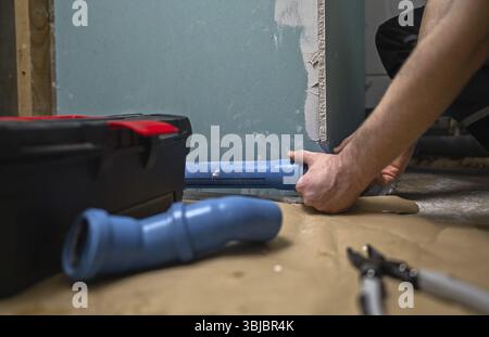 Man assembling plumbing pipes in the bathroom Stock Photo