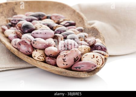 Pinto beans on wooden scoop on beige table cloth. Healthy eating, agriculture background Stock Photo