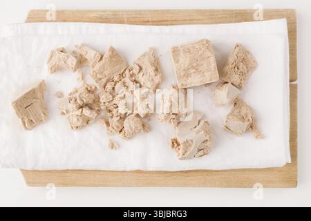 Fresh pressed yeast blocks on wooden board isolated on white background Stock Photo