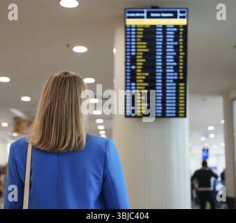 Woman in business suit in checking her flight in airport Stock Photo