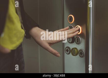 Woman pressing button inside elevator Stock Photo