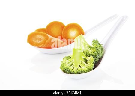 Broccoli and carrot pieces on white spoon isolated on white background Stock Photo