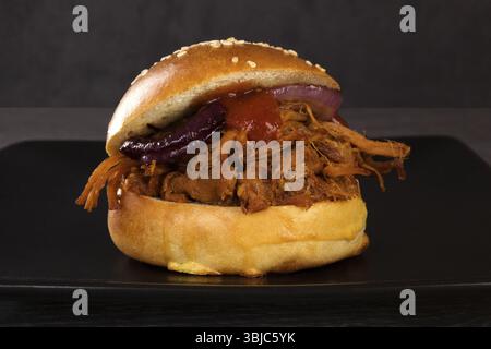 Pulled pork burger on black plate on dark background Stock Photo