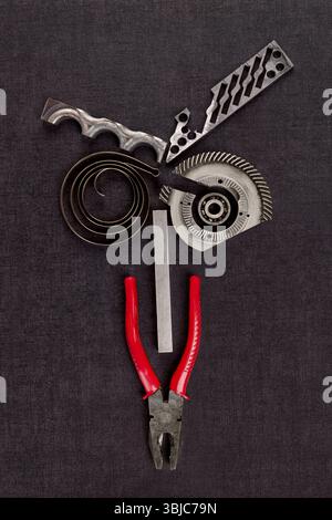 Screws, cogwheels and mechanical components on black surface from above Stock Photo