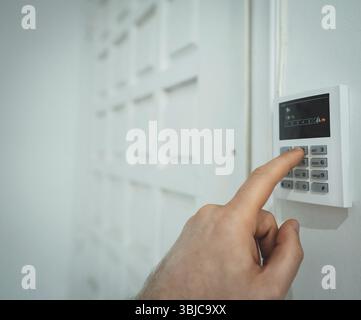 Man putting code in alarm system panel at home Stock Photo