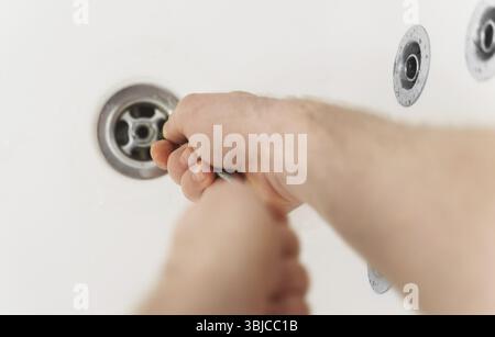 Plumber using drain snake to unclog bathtub Stock Photo