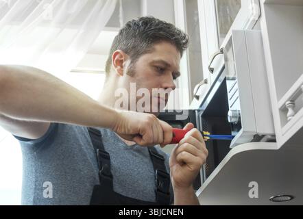 Male technician repairing microwave oven at home Stock Photo