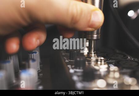 Sound engineer plugging jack audio cable on studio mixer Stock Photo