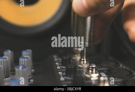Sound engineer plugging jack audio cable on studio mixer Stock Photo