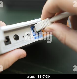 Man plugging internet cable into wifi router Stock Photo