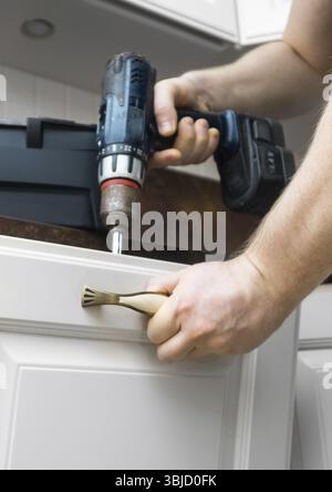 Professional handyman assembling kitchen door cabinet Stock Photo