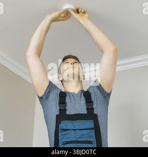 Man mounting smoke detector on the ceiling Stock Photo