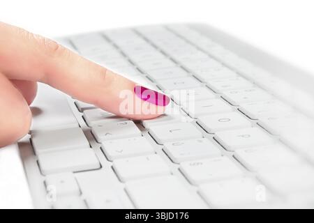 Female finger with red fingernail touching silver and white keyboard, selective focus. Help desk concept Stock Photo