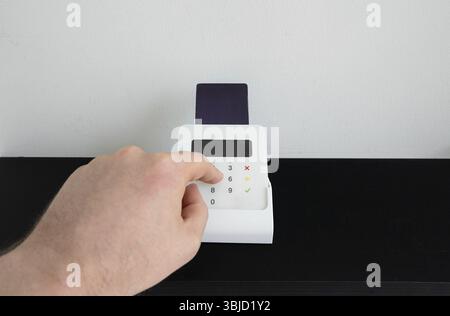 Man's hand entering a PIN code on a wireless payment terminal Stock Photo