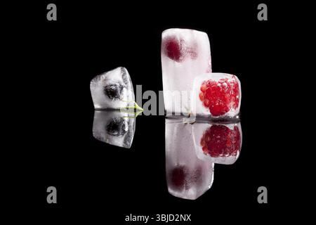 Fresh raspberry, cherry and blackcurrant frozen in ice blocks isolated on black background. Fresh summer concept Stock Photo