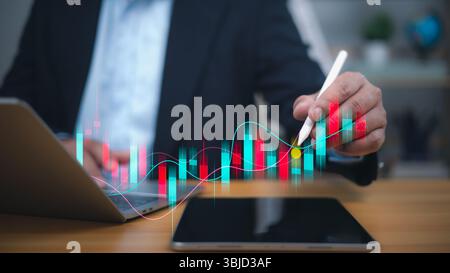 A businessman uses a stylus to analyze a dynamic, fluctuating financial graph with red and blue bars, symbolizing investment analysis, stock market tr Stock Photo