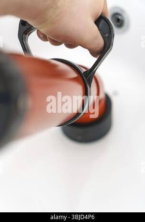 Plumber unclogging bathtub with professional force pump cleaner Stock Photo