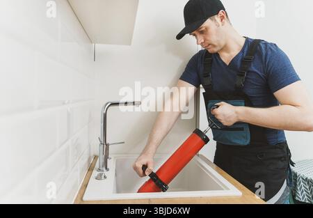 Plumber unclogging kitchen sink with professional force pump cleaner Stock Photo