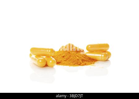 Turmeric (curcumin) powder heap and capsules isolated on white background. Anti-inflammatory nutritional supplement Stock Photo