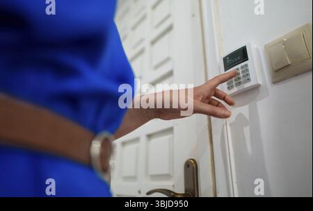 Woman putting code in alarm system panel at home Stock Photo