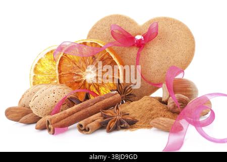 Natural traditional christmas background with orange, almond, various nuts and spices decorated with pink ribbon isolated on white background. Traditi Stock Photo