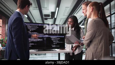 Software Developer Leading Late-Night Meeting With Programmer Team In Office Stock Photo