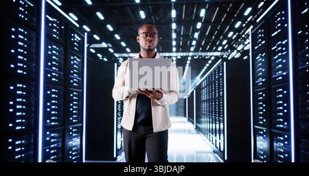 African American Data Engineer Configures Server Rack In Data Center. Stock Photo
