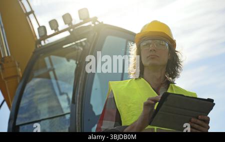 Excavator operator in hard hat using tablet pc Stock Photo