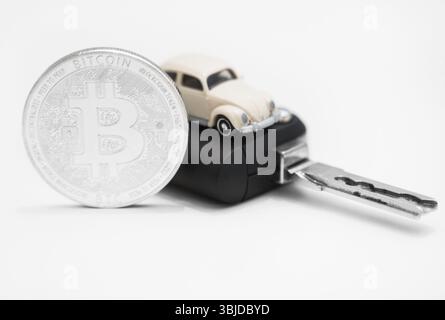 Silver physical bitcoin and car key on white background Stock Photo