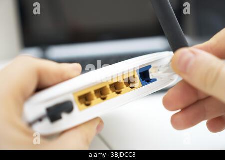 Man plugging internet cable into wifi router Stock Photo