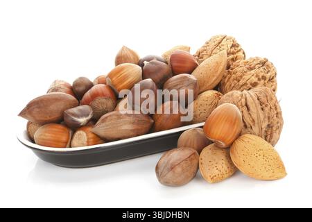 Various nuts, walnuts, hazelnuts, almond and chestnuts in black bowl isolated on white background. Seasonal healthy nuts Stock Photo