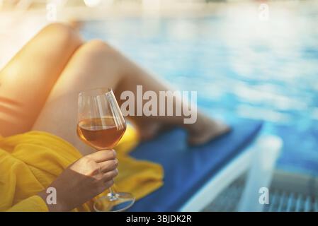 Frau mit Wein, die sich am Swimmingpool entspannt Stock Photo