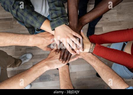 Diverse group of people joining hands in circle, symbol of unity, trust, teamwork and friendship. Stock Photo