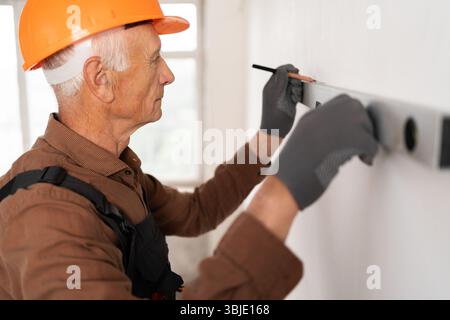 Builder with spirit level measure wall for maintenance, home repair. Construction handyman Stock Photo