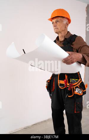 Senior retired architect builder holding plan of rooms. civil engineer working with documents. building and home renovation Stock Photo