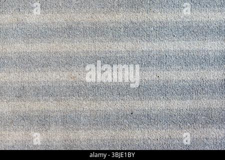Close-up of horizontally striped carpet texture, alternating gray and beige bands with a visible rough surface. Stock Photo