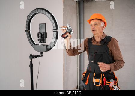 Male builder blogger is broadcasting live on social networks. Stock Photo