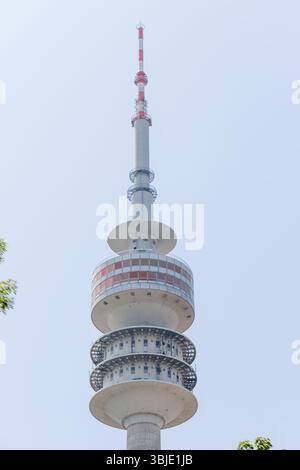 The image features a tall, concrete and steel communication tower with a red and white striped antenna against a bright blue sky. Stock Photo