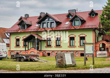 June 10, 2025 - Teschendorf‑Germany: Traditional village house in Märkisch Brandenburg under renovation, trailer for mini excavator on site laying fib Stock Photo