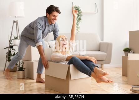 Husband Having Fun Riding His Wife In Moving Box Stock Photo