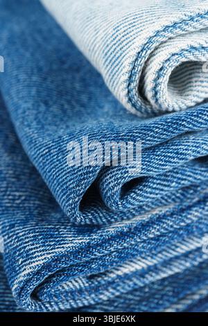 Pile of folded textiles, various shades of blue jeans fabric, denim cloth, are stacked on top of each other in store setting, showcasing different tex Stock Photo